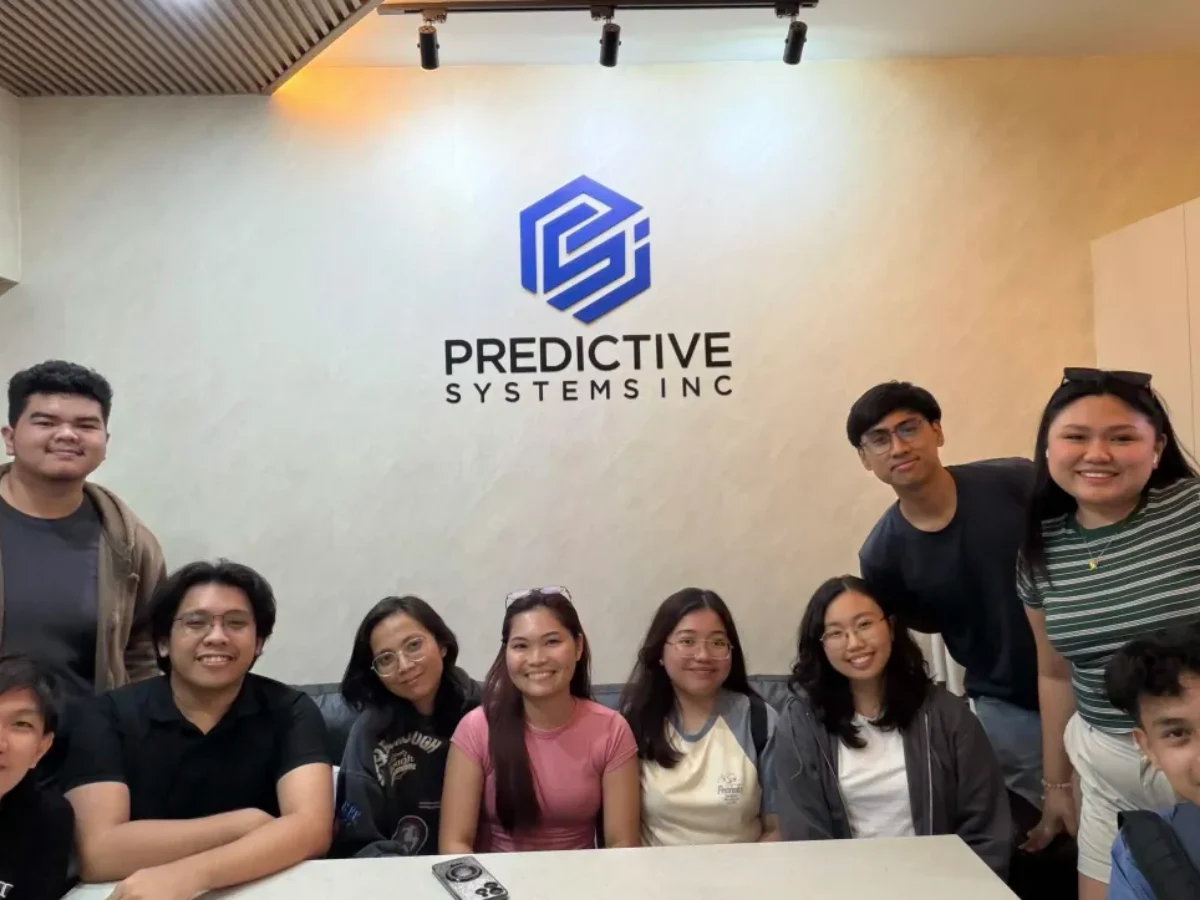 Ten of the PSI team gathered under the Predictive Systems sign on the office wall.